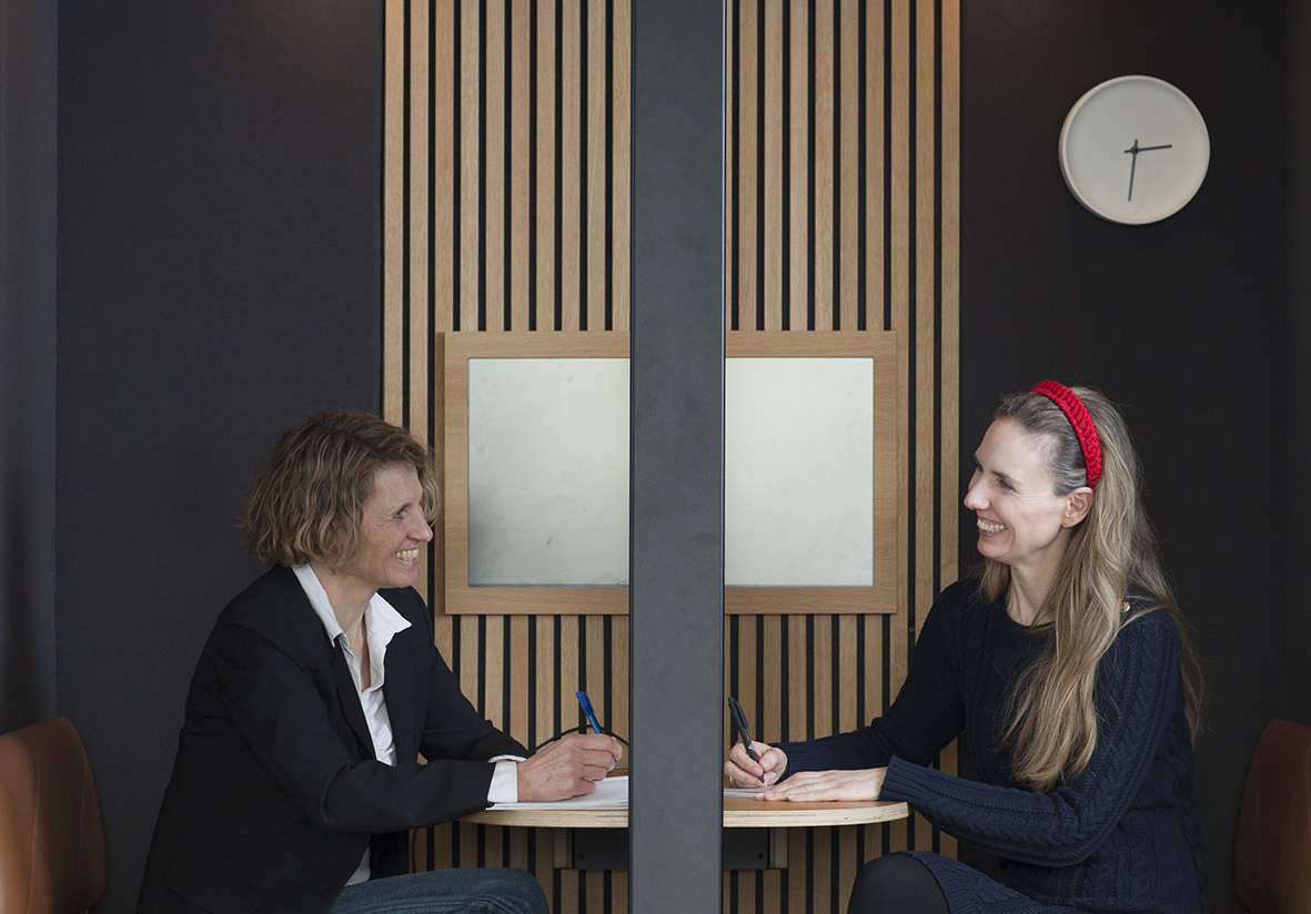 To smilende kvinder holder møde i en mutebox